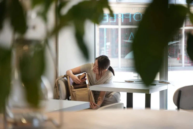 Woman sitting at a table in a modern cafe with large windows.
